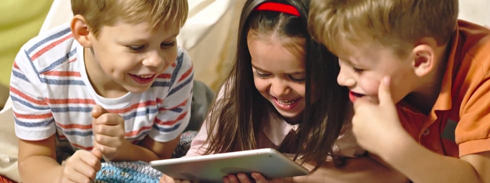 3 kids laughing looking at tablet