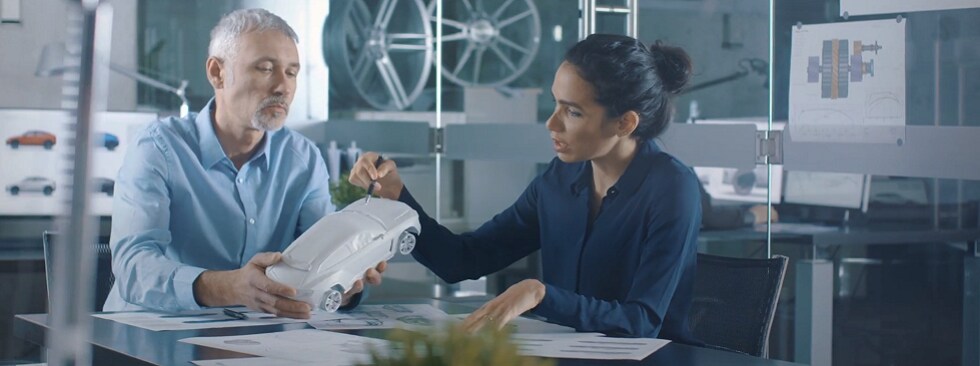 Two people examine prototype automobile