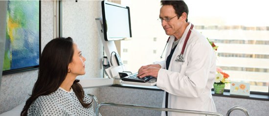 Photo of a doctor at a patient's bedside using Dell technology