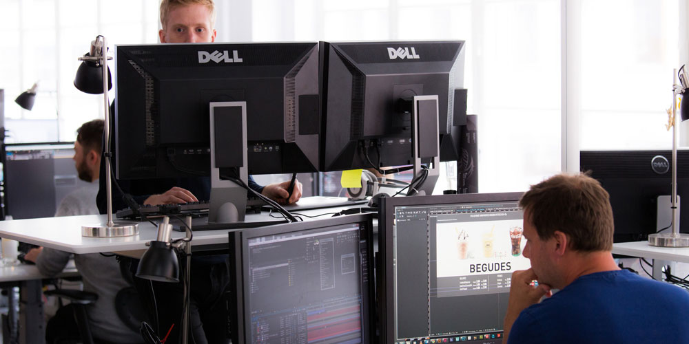 two men in an office working with multiple monitors
