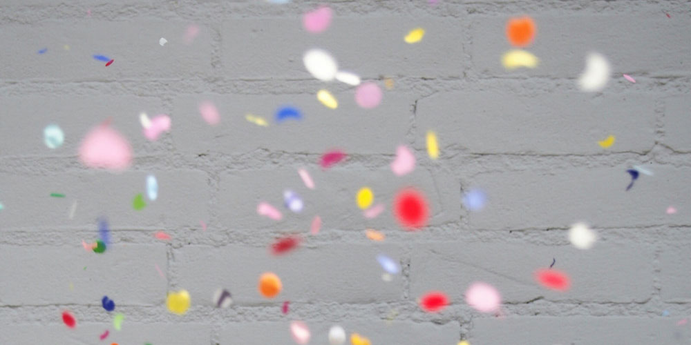 confetti falling in front of a white brick wall