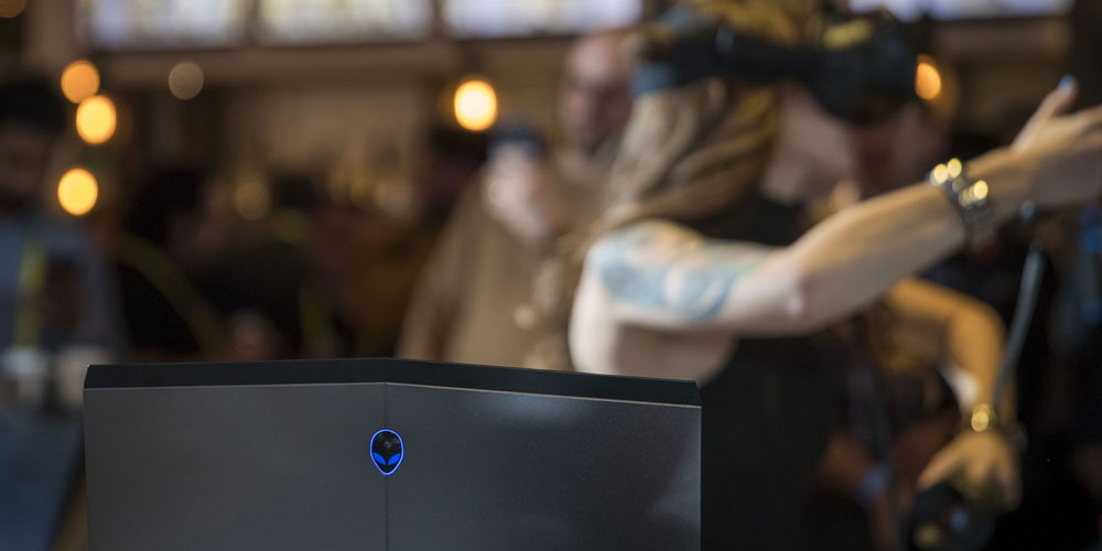 woman in virtual reality headset behind alienware laptop