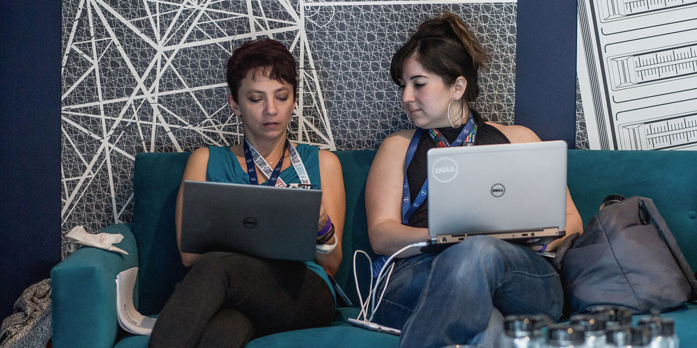 two women seated with dell laptops on their laps