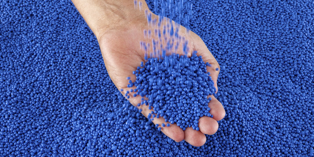 hand holding blue plastic pellets
