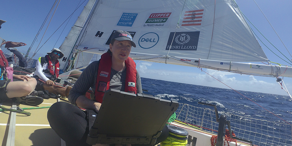 Samantha Harper on the deck of Dare to Lead clipper ship using Dell Rugged Latitude laptop