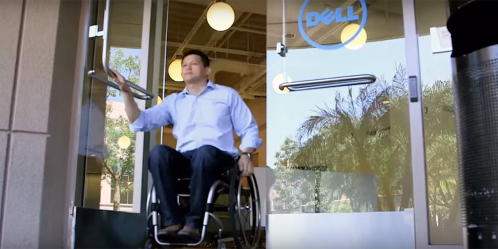 a man in a wheelchair exits a Dell office building