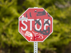 A stop sign with graffiti and stickers. 