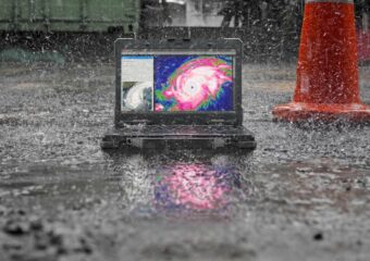 Rugged Latitude 7330 with hurricane satellite image on screen, on the ground in the rain