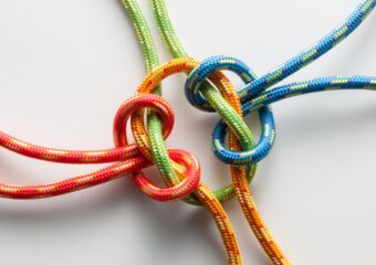 Four different colored strings are tied together to form a knot.