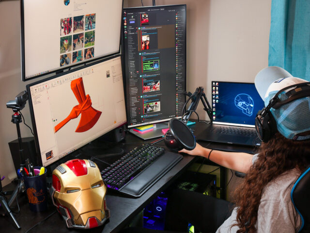 Emily Yarid designing with Dell Precision 5750 mobile workstation and Dell UltraSharp 27" monitors. Iron Man helmet in lower left corner of image on her desk.