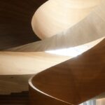 Looking up a curving wooden staircase inside a building.