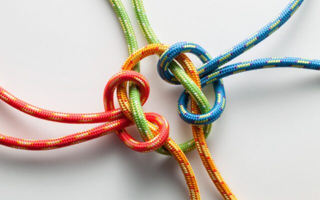 Four different colored strings are tied together to form a knot.