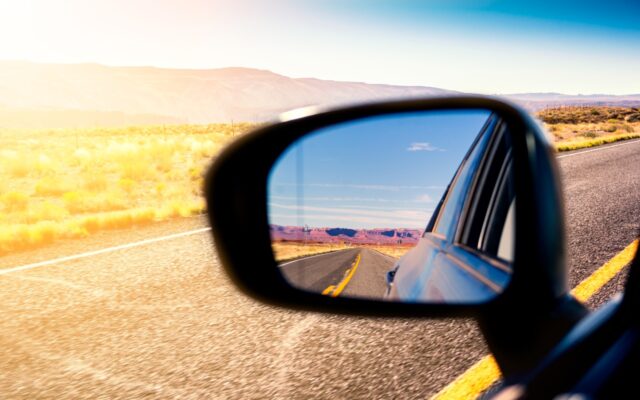 Close up of a car side mirror reflecting a mountain desert scene that was just driven by.