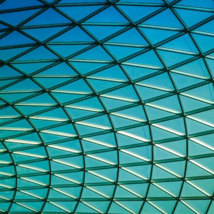 Geometric grid of glass windows with blue sky beyond.