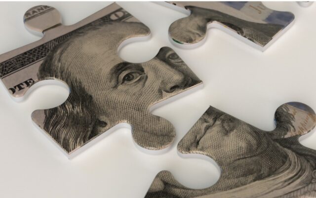 A U.S. one hundred dollar bill in jigsaw puzzle pieces, representing challenges of financial management.