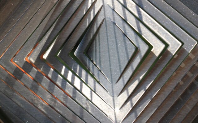 Abstract image of silver metal design in concentric diamond shape.