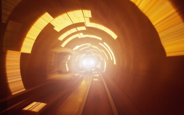 High speed movement in tunnel, with a light in the distance. In light yellow and darker orange colors.