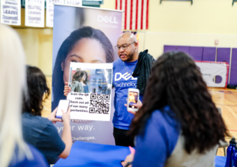 Young African-American man holds a poster with a QR code at a Dell Technologies college recruiting event.
