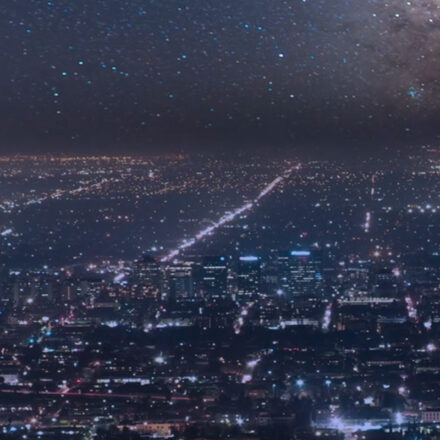 Aerial view of a cityscape at night with stars in the background.