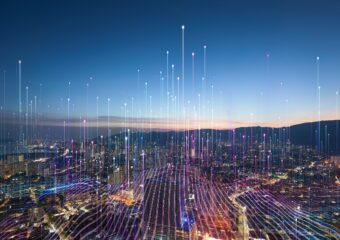 Data connection lines digitally superimposed over a cityscape in low light, representing 5G and AI data connections and processing.