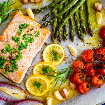 Salmon cooked with asparagus, tomatoes and other vegetables on a pan sheet.