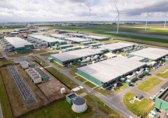 Aerial view of a data center with wind turbines nearby.