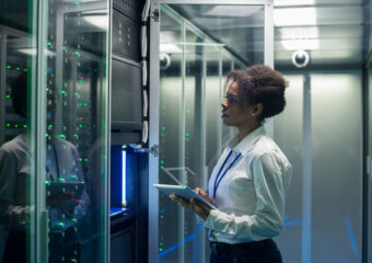 Female IT professional checking status of servers in data center.