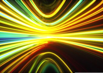 Digital abstract graphic of glowing bands of light in shades of green, yellow, and orange that move toward the background,