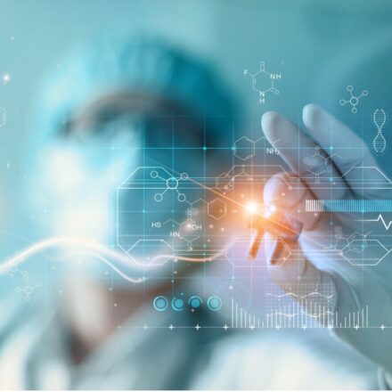 Image of a doctor in mask, gloves, and hair covering with a digital representation of a DNA molecule in their hand. Image is against a light blue background and focus is on their left hand.