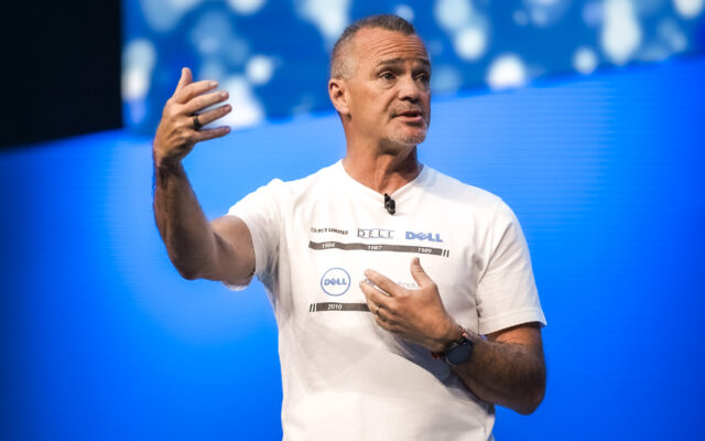 Jeff Clarke, Dell Technologies vice chairman and co-COO, on stage wearing a white t-shirt showing a timeline of Dell's corporate logos, speaks onstage at Day 2 of Dell Technologies World.