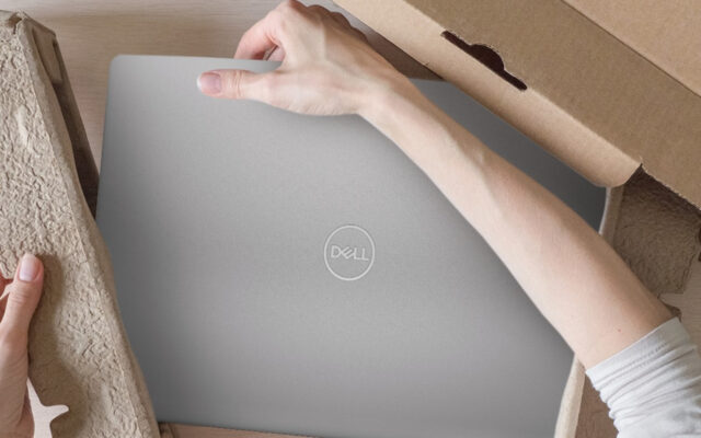 Woman's right hand holds a Dell Latitude 15 9510 2-in-1 Touch Notebook as she unboxes it from its packaging.