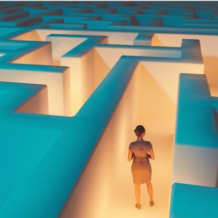 Elevated perspective of a woman navigating a maze, following the lighted path to guide her to destination.