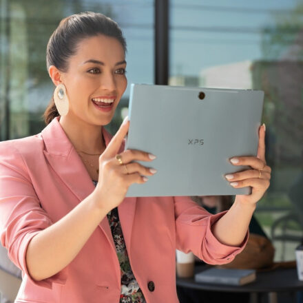 Young business woman holds a Dell XPS 9315 2-in-1 up in tablet mode for a video conference.