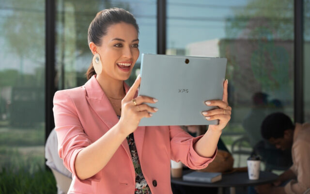 Young business woman holds a Dell XPS 9315 2-in-1 up in tablet mode for a video conference.