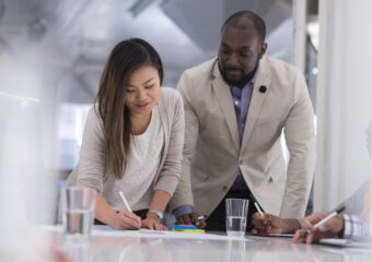Asian female and Black man in business casual attire sign business documents.
